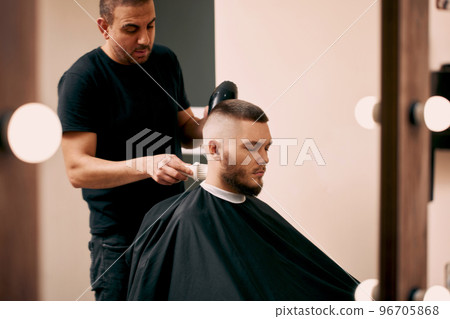 Barber shaving bearded man in barber shop 96705868