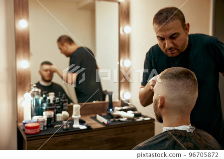 Barber shaving caucasian man in barber shop 96705872