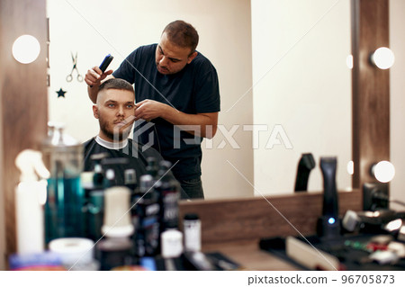Barber shaving caucasian man in barber shop 96705873