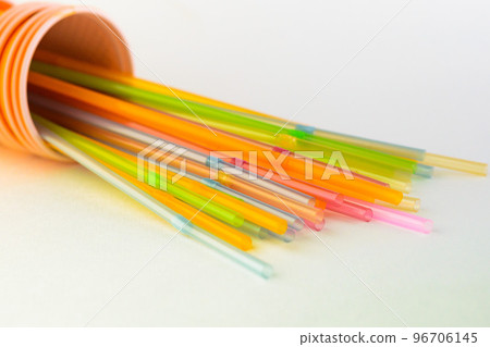 Multicolored plastic tubules in an orange cup on a white background Multicolored plastic tubules in an orange cup on a white background 96706145