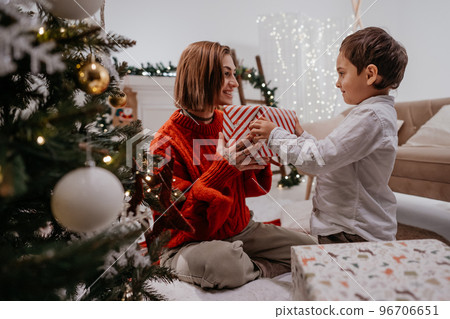 Lovely boy giving present to his mother under the Christmas tree 96706651