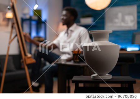 African american artist creating professional sketch of ceramic vase on easel in modern art studio. Drawing student creating pencil masterpiece on canvas in home crafts studio at bedroom. 96706856