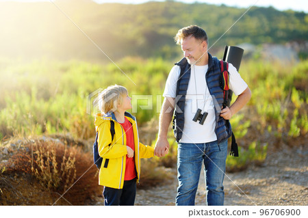 Cute schoolchild and his mature father hiking together and exploring nature. Child learning survival skills and orienteering. Concepts of adventure, scouting and kids tourism 96706900