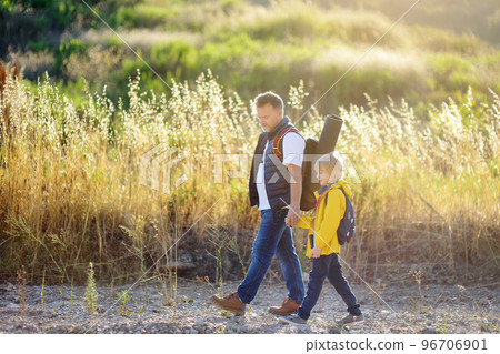 Cute schoolchild and his mature father hiking together and exploring nature. Child learning survival skills and orienteering. Concepts of adventure, scouting and kids tourism 96706901