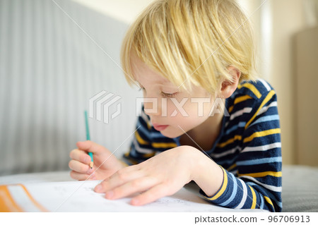 Elementary student boy doing homework at home. Child learning to count, solves arithmetic examples, doing exercises in workbook. Math tutorial. Preparing preschooler baby for school. Education 96706913