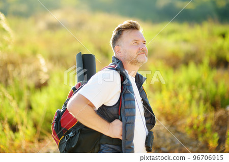 Mature man hiking on sunny summer day. Adventure concept. Solo travel. Hitch-hiking. Backpacking trip 96706915