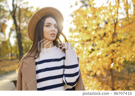portrait of attractive stylish smiling portrait of attractive stylish smiling woman with long hair walking in the park, dressed in warm brown coat autumn trendy fashion, street style wearing hat 96707410