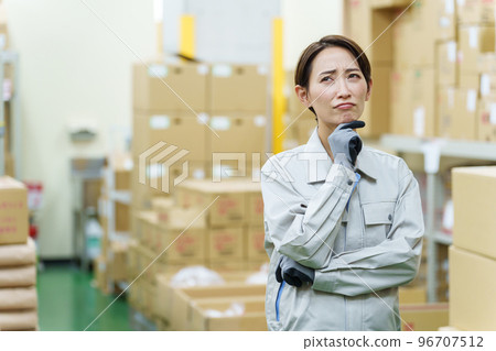 A female worker who is worried in the warehouse 96707512