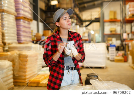 Female warehouse worker using smartphone to check quantity of goods Female warehouse worker using smartphone to check quantity of goods 96709202