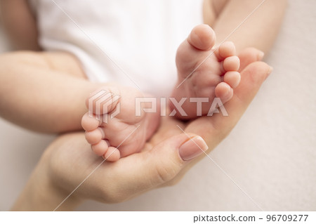 Children's foot in the hands of mother, father, parents. Feet of a tiny newborn close up. Little baby legs. Mom and her child. Happy family concept. Beautiful concept image of motherhood stock photo.  96709277