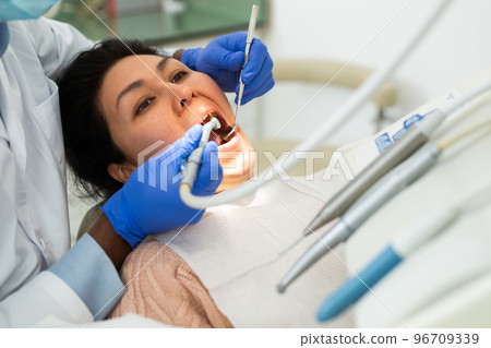 Dentinst examining oral cavity of asian woman with tools in dental clinic 96709339