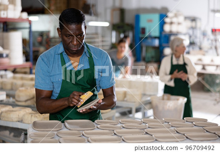 Male ceramist polishing new clay plates Male ceramist polishing new clay plates 96709492