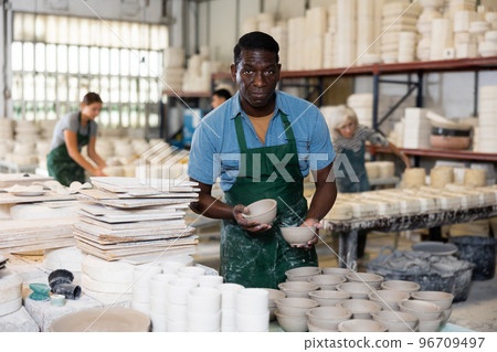 Portrait of african american man displaying cups at workshop Portrait of african american man displaying cups at workshop 96709497
