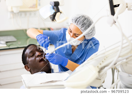 Dentist is treating male patient which is sitting in chair Dentist is treating male patient which is sitting in chair 96709523