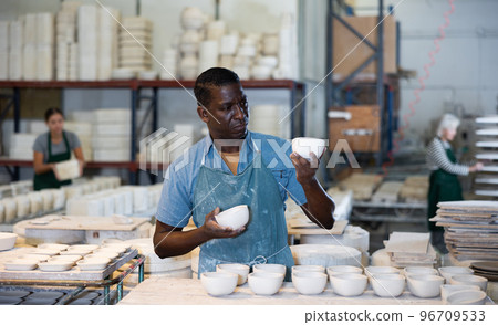 African american man checks quality of pottery after being removed from plaster mold 96709533
