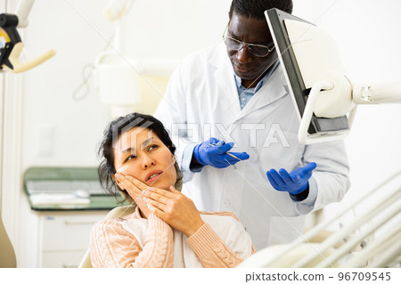 Asian woman with toothache sitting in chair at dentist appointment 96709545