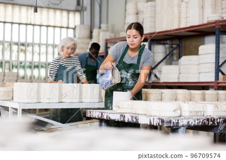 Pouring slip mass into plaster molds at pottery factory Pouring slip mass into plaster molds at pottery factory 96709574