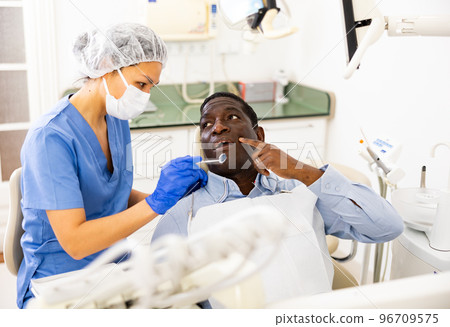 Patient complaining to female dentist about toothache at dental office Patient complaining to female dentist about toothache at dental office 96709575
