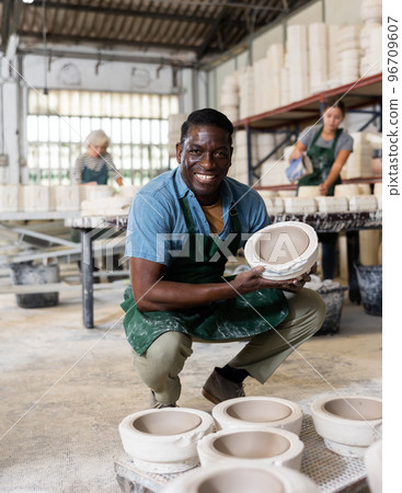 Pleased african american worker demonstrates half of plaster mold for pottery in pottery factory 96709607
