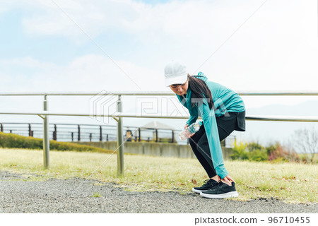 Asian woman in sportswear hurting and touching her ankle while exercising Asian woman in sportswear hurting and touching her ankle while exercising 96710455