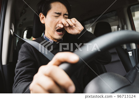 一個男人開車，困倦，打噴嚏的形象 96713124