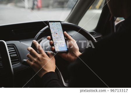 一個男人一邊開車一邊看智能手機的圖片 一個男人一邊開車一邊看智能手機的圖片 96713317
