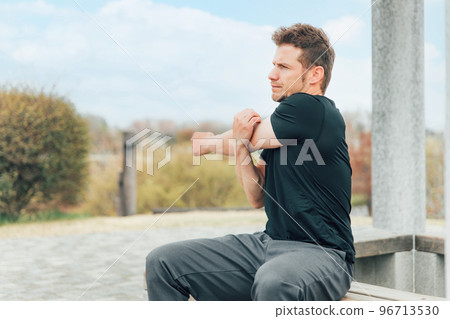 Caucasian man in sportswear stretching armpits and arms before exercising, doing flexible exercises, and warming up Caucasian man in sportswear stretching armpits and arms before exercising, doing flexible exercises, and warming up 96713530