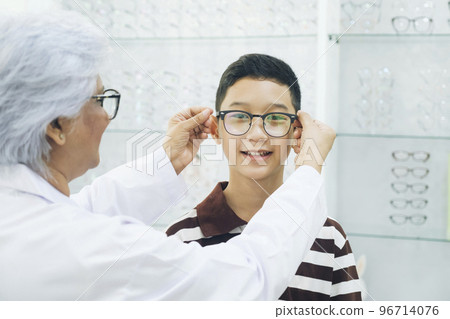 Smart young boy trying out new eyeglasses. 96714076
