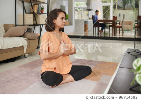 Young woman practicing yoga when her wife eating breakfast in the background 96714592
