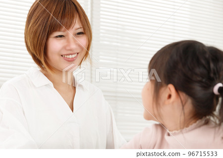 一個女人微笑著和她的孩子交談。幫助學習和教育的育兒媽媽形象。 一個女人微笑著和她的孩子交談。幫助學習和教育的育兒媽媽形象。 96715533