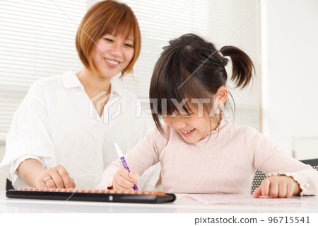 Student child and teacher in cram school or abacus classroom. An image of supporting a child while watching over it happily. Student child and teacher in cram school or abacus classroom. An image of supporting a child while watching over it happily. 96715541