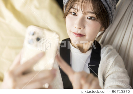 Young woman lying on a hammock and looking at her smartphone Home Camp Home Camp Camping Image 96715870