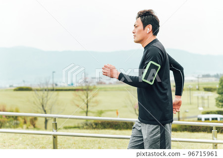 穿著運動服的亞洲男子在跑步訓練期間在智能手機上使用健身應用程序 96715961