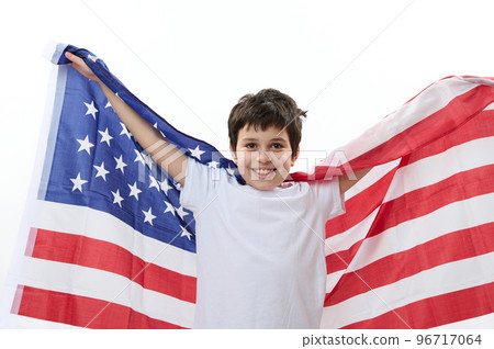 Multiethnic happy patriotic preteen child boy, smart teenager, smiling a cheerful toothy smile, looking at camera, carrying American flag. Citizenships. Immigration concept. 4th July. Independence Day 96717064