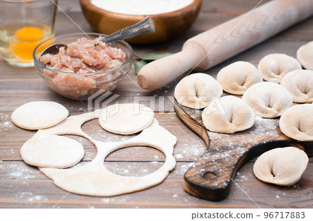 The process of molding dumplings and ingredients for cooking on a wooden table The process of molding dumplings and ingredients for cooking on a wooden table 96717883