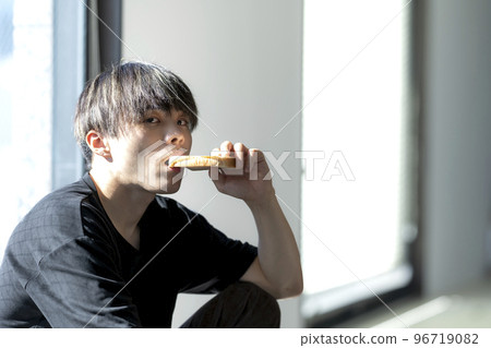 A young man eating bread 96719082