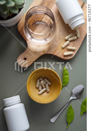 White pill bottles on green background. Health care food supplements, vitamins and medicaments White pill bottles on green background. Health care food supplements, vitamins and medicaments 96719377