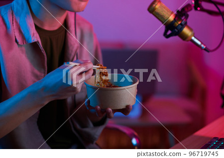 Cropped image of videogamer eating noodles when filming video for his blog Cropped image of videogamer eating noodles when filming video for his blog 96719745