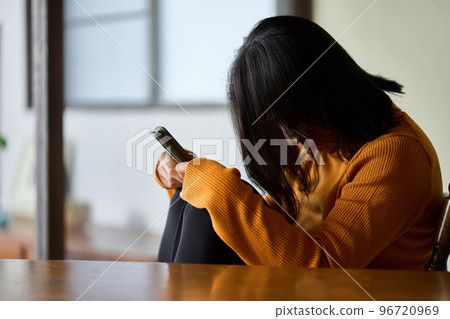 A woman who feels depressed looking at her smartphone 96720969