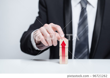 Wooden blocks with red arrow icon, businessman in suit holding cube on white background 96721262