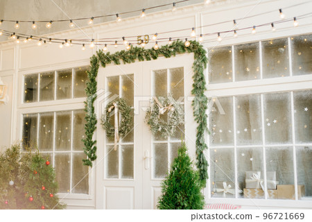 Christmas facade of the house. White doors with Christmas wreaths on the doors and retro light bulbs and lights 96721669