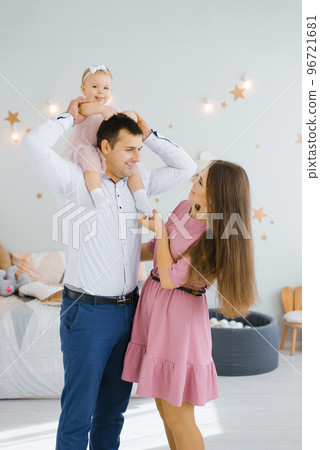 The daughter smiles and rolls on her father's neck. Happy mom is standing by The daughter smiles and rolls on her father's neck. Happy mom is standing by 96721681