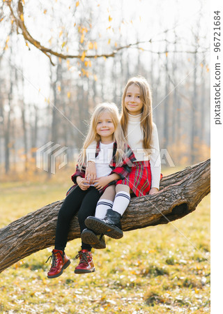 Smiling children sit on a tree in the autumn Park Smiling children sit on a tree in the autumn Park 96721684