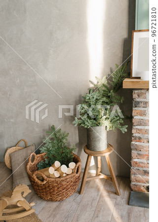 A basket for firewood by the fireplace and fir branches in a tin bucket. Cozy atmosphere at home before Christmas. 96721810