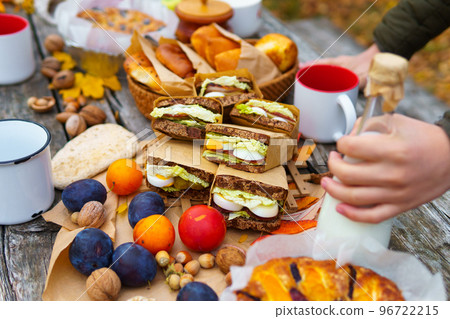picnic in the autumn season, food on a wooden table, hot tea, pastries and sandwiches picnic in the autumn season, food on a wooden table, hot tea, pastries and sandwiches 96722215