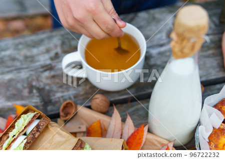 picnic in the autumn season, food on a wooden table, hot tea, pastries and sandwiches 96722232