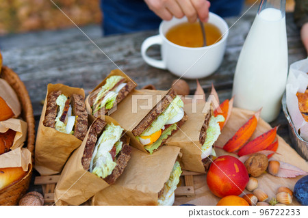 picnic in the autumn season, food on a wooden table, hot tea, pastries and sandwiches 96722233