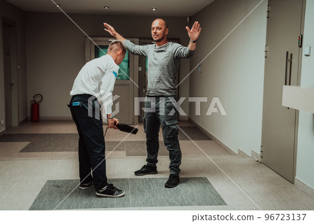 Security guard making body searching procedure on man for finding hidden objects before entering in treasury department Security guard making body searching procedure on man for finding hidden objects before entering in treasury department 96723137