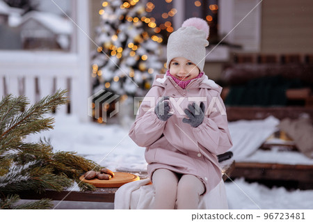 Happy cute girl sitting on the porch of the house for christmas 96723481