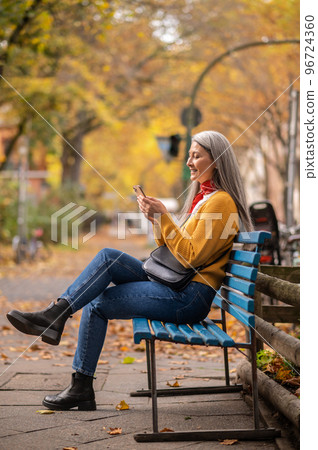 Good-looking woman sitting on the bench and talking on the phone 96724360